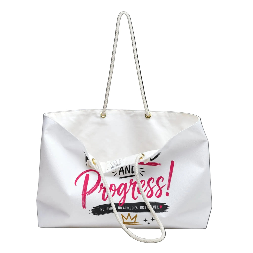 A white canvas tote bag with white rope handles, featuring a graphic print on the front that reads 'AND Progress!' in pink and black, with a small gold crown logo at the bottom.