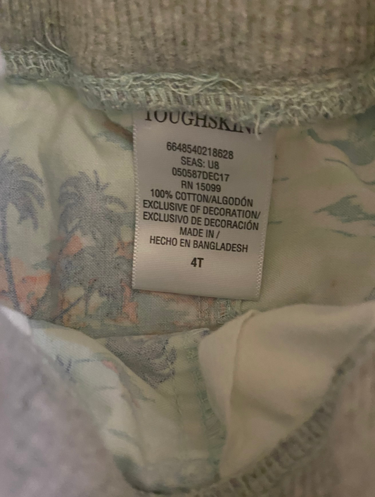 Close-up of a garment's interior neck label reading TOUGHSKIN, with a light gray ribbed knit collar and a patterned lining in pale green, beige, and soft pink.