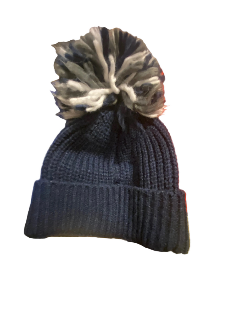 Blue knit beanie with a pom-pom on a colorful blanket