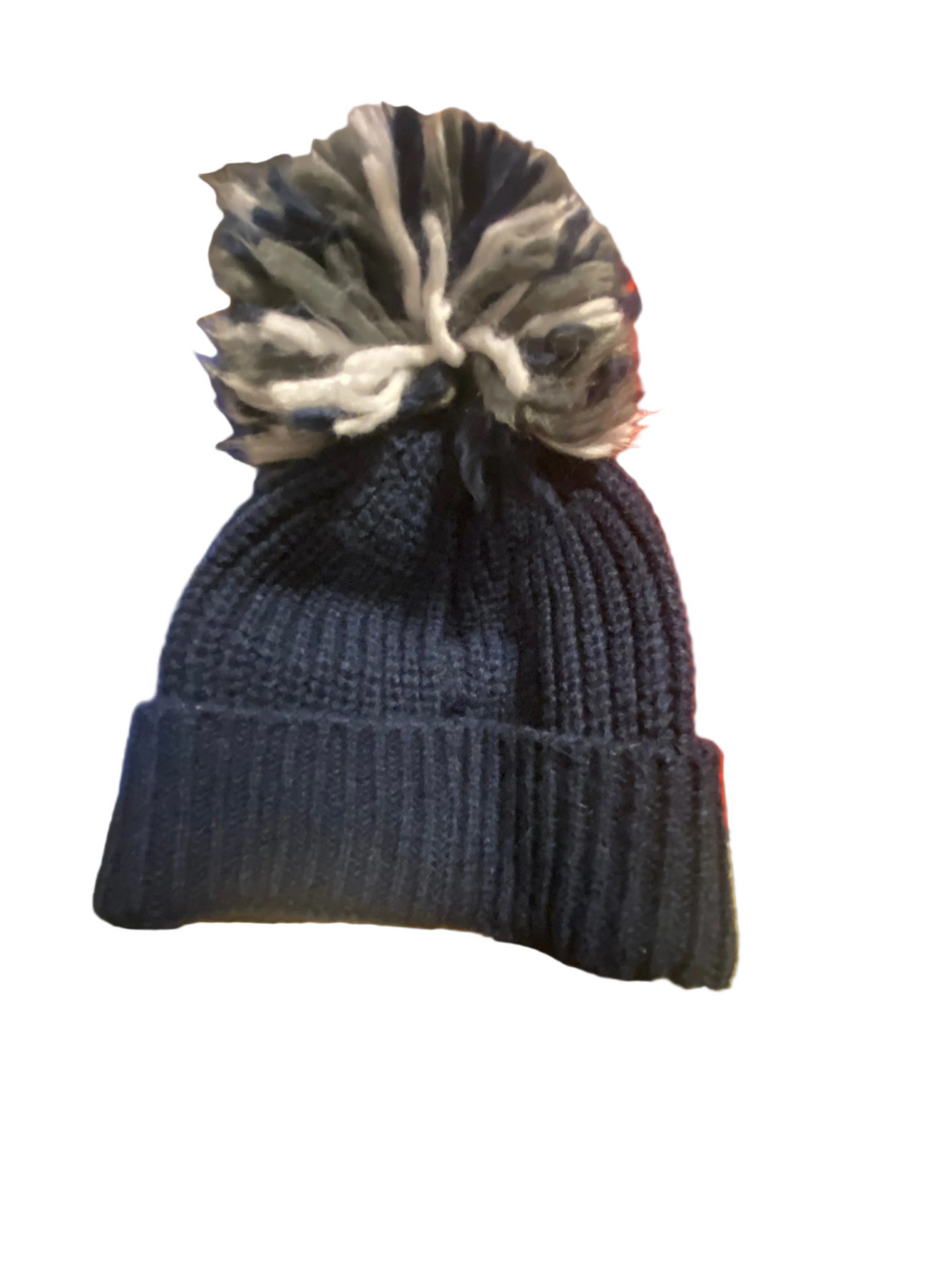 Blue knit beanie with a pom-pom on a colorful blanket