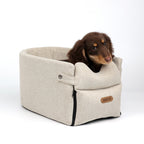 Dog sitting in a beige pet carrier with a white background